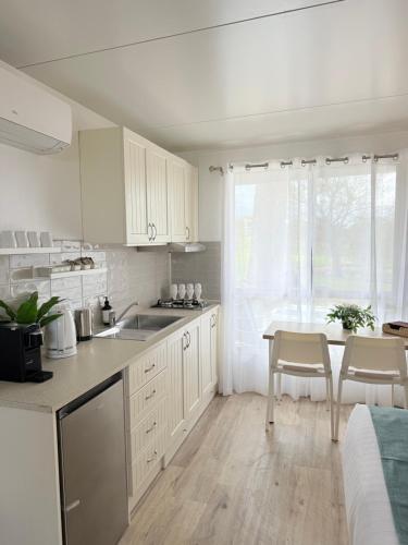 a kitchen with white cabinets and a table with chairs at Hickey Vale Farm Studio in Broadford