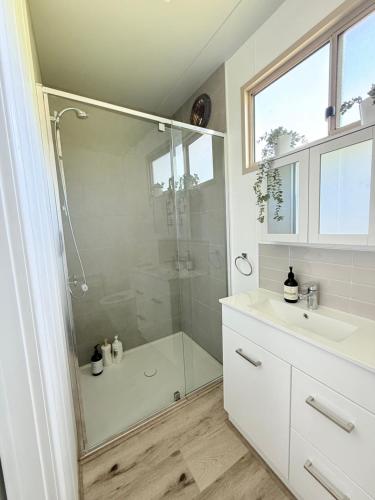 a white bathroom with a shower and a sink at Hickey Vale Farm Studio in Broadford