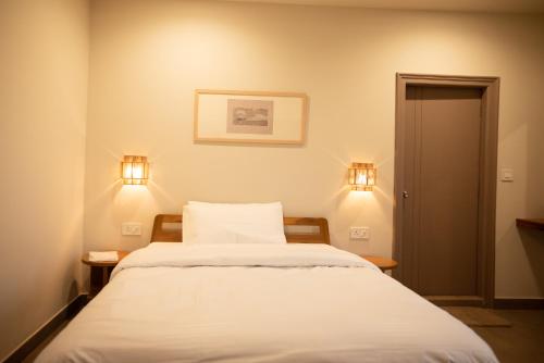 a bedroom with a bed with white sheets and lights at Ara Ki Serviced Apartments in Kohīma