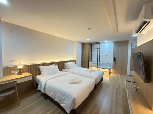 a hotel room with two beds and a desk and a television at Armass Residence in Bangna