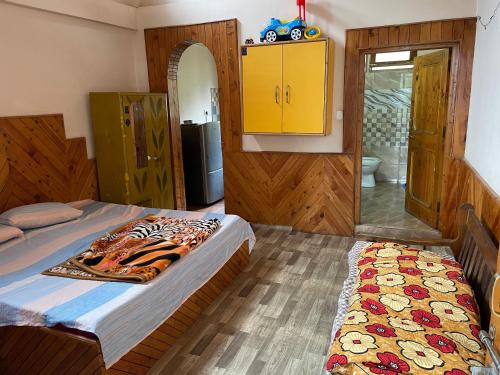 a bedroom with a bed and a yellow cabinet at Kingdom Homestays in Manāli