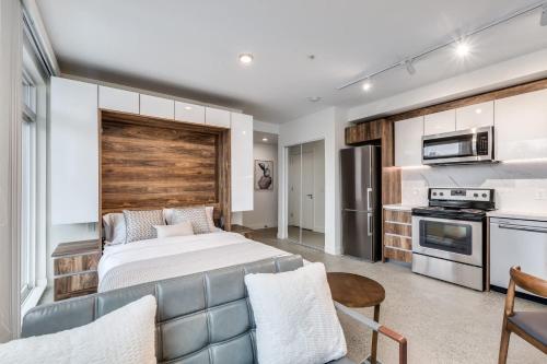 a bedroom with a large bed and a kitchen at Modern Downtown Studio Bedroom Walk Everywhere in Vancouver