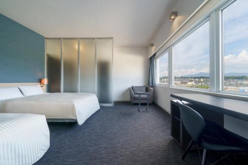 a hotel room with a bed and a desk and window at Hotel Vista Kumamoto Airport in Ozu