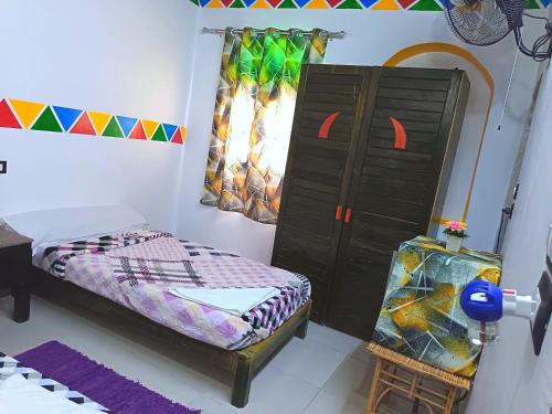 a bedroom with a bed and a dresser and a chair at Shellaly Ca Nubian Guest2 House in Jazīrat Salūjah