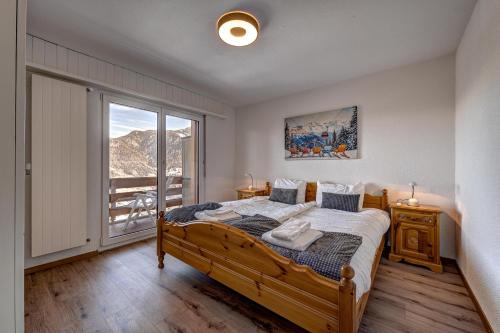 a bedroom with a bed and a large window at Appartement Tzoum'Azur 6 in La Tzoumaz
