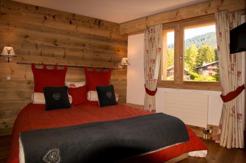 Schlafzimmer mit einem Bett mit roten Kissen und einem Fenster in der Unterkunft Le Bristol - Villars Bristol Apartments in Villars-sur-Ollon