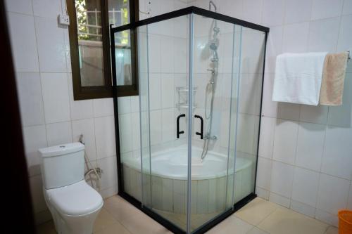 a glass shower in a bathroom with a toilet at Kaze Consolidate Home Inn in Kigali
