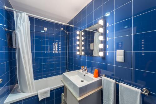 a blue tiled bathroom with a sink and a mirror at Hotel Made Inn in Portimão