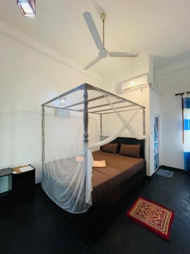 a bedroom with a bed with a mosquito net at Screwpine Beach Villa in Hiriketiya