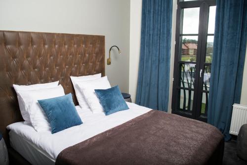 a bedroom with a bed with blue pillows and a window at Vytautas Mineral SPA in Birštonas