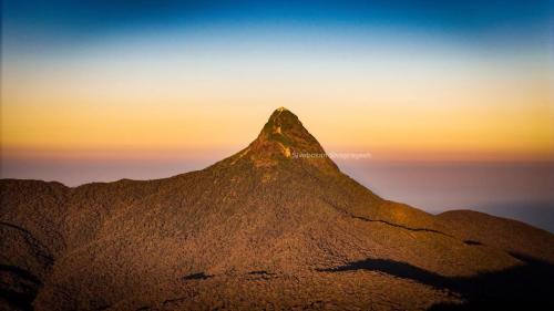 a mountain peak with a sunset in the background at Adams Peak Lake Resort in Nallathanniya