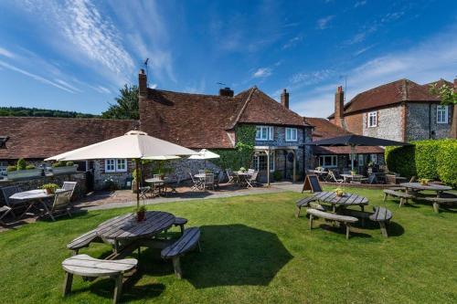 a patio with tables and chairs and an umbrella at The Fox Goes Free in Chichester
