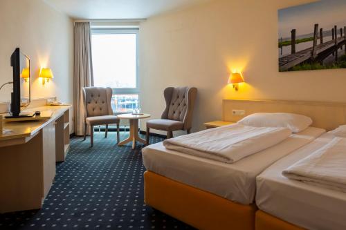 a hotel room with two beds and a desk and chairs at Trip Inn Hotel Astoria in Göttingen