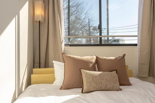 a bed with pillows in a bedroom with a window at Mi-Hotel Nakano- Shinjuku Direct 中野南台 in Tokyo