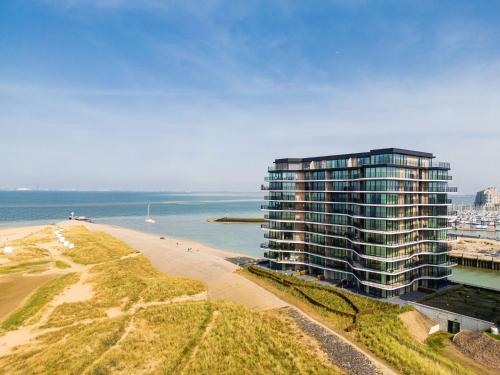 a tall building next to a beach next to the ocean at Dormio Breskens Apartments & Penthouses in Breskens