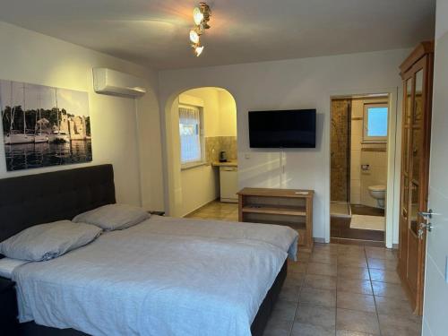 a bedroom with a bed and a bathroom with a television at Villa Nikki in Bilice