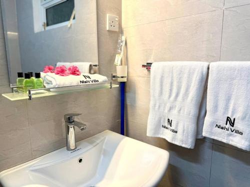 a bathroom with a sink and towels and a mirror at Nishi Villa in Negombo