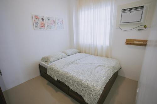 a small bed in a white room with a window at Villa Serena in Dauis