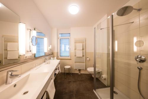 a bathroom with two sinks and a shower and a toilet at Landhotel Endhart in Landsberg am Lech