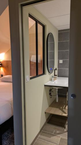 a bathroom with a sink and a mirror and a bed at Le Rocher Du Cerf in Le Lioran