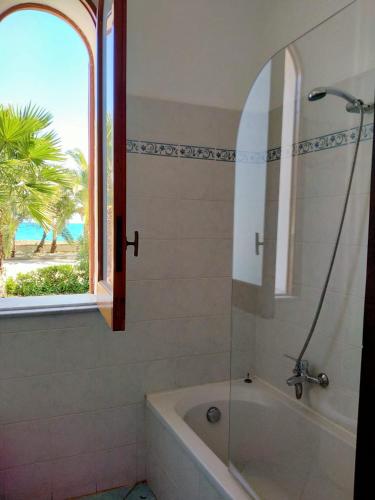 a bathroom with a bath tub and a window at Testa di Monaco Natural Beach in Capo dʼOrlando