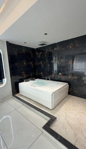 a white bath tub in a room with black walls at Hotel Palash Icon in Ahmedabad