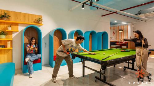 a group of people playing pool in a room with a table at Zostel Noida in Noida