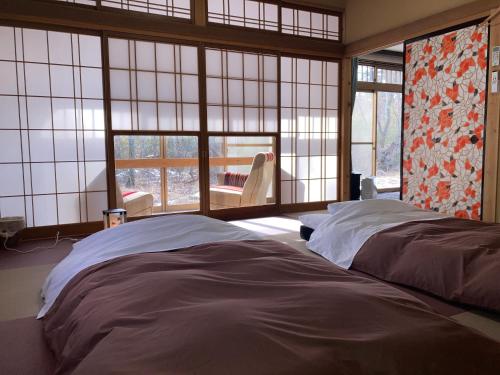 a bedroom with a large bed and large windows at 安曇野市穂高温泉郷Vila湯仙望 in Azumino