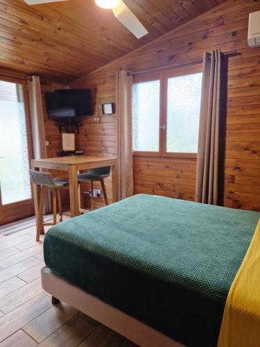 a bedroom with a bed and a desk with a television at KAZBONZAMIS in Sainte-Clotilde