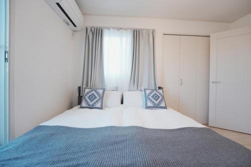 a bedroom with a bed with blue and white pillows at Dorothy Inn Spacious 4LDK New Build 97sqm Up to 10 Guests Free Private Parking Near JR Higashi Jujo Station 3 Minute Walk in Tokyo