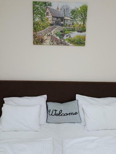 a bed with white pillows and a picture of a house at Apartman Petrovic in Rudnik