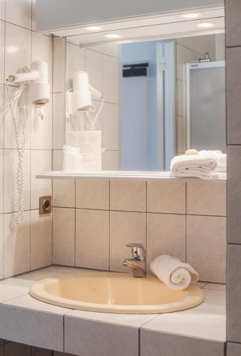 a bathroom with a sink and a mirror at Hôtel La Tour des Anglais in Mayenne
