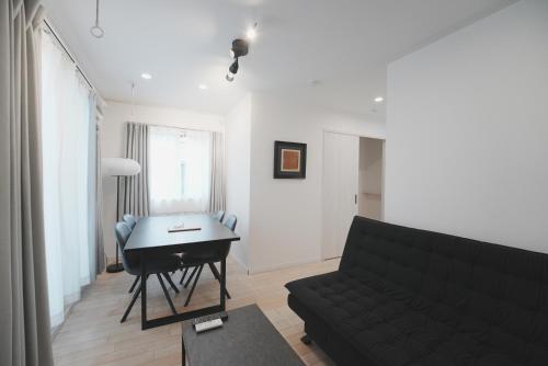 a living room with a black couch and a piano at Dorothy Inn Spacious 4LDK New Build 97sqm Up to 10 Guests Free Private Parking Near JR Higashi Jujo Station 3 Minute Walk in Tokyo