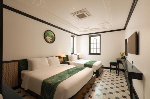 a hotel room with two beds and a television at C'Lau Hotel Ninh Binh - A Gem Nestled in Ancient Quarter in Ninh Binh