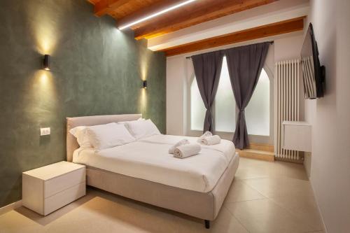 a bedroom with a large white bed and a window at Bohemia Apartment in Calmasino