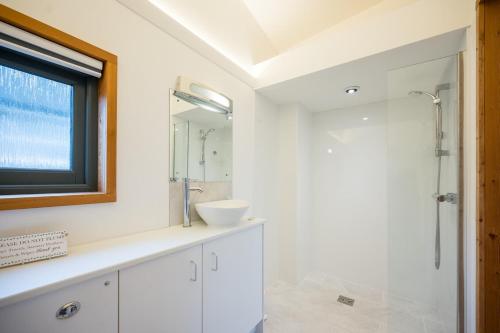 a white bathroom with a sink and a shower at The Orchard Annexe, Framlingham in Framlingham