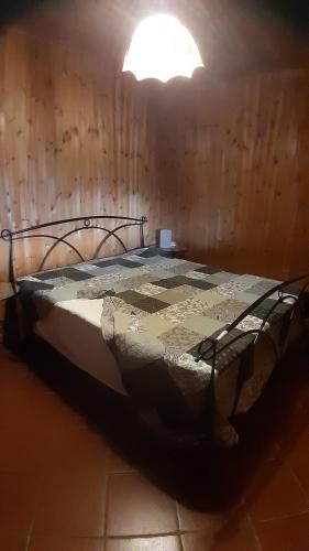 a bed in a room with a light above it at La Baita Baretana 2 in Barete