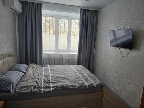a bedroom with a bed and a tv on the wall at Возле Нарыка in Ekibastuz
