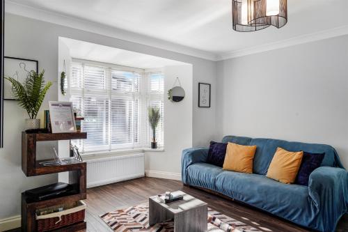 a living room with a blue couch and a table at 4 BR 6 Beds 3 Bath PS4, Pool Table Parking x4 Close to Legoland & Windsor in Maidenhead