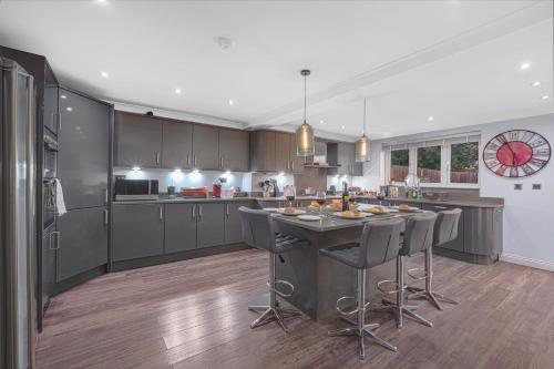 a kitchen with a island with bar stools in it at 4 BR 6 Beds 3 Bath PS4, Pool Table Parking x4 Close to Legoland & Windsor in Maidenhead