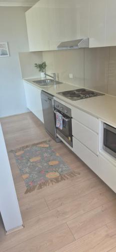 a kitchen with a stove and a rug on the floor at Spacious Apartment Oasis in Bankstown