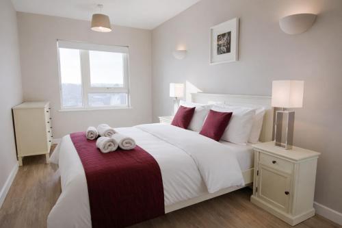 a bedroom with a large white bed with red pillows at Roomspace Serviced Apartments - Vertex House in Croydon
