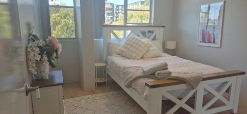 a small bed in a room with windows at Spacious Apartment Oasis in Bankstown