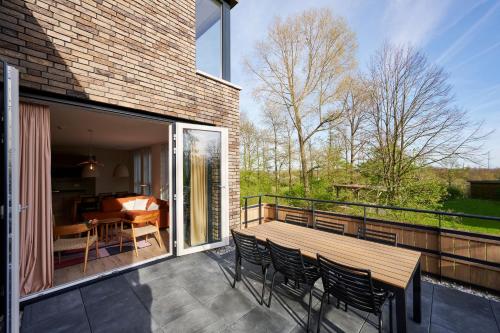 a patio with a wooden table and chairs on a balcony at Dormio Resort Maastricht Castellum Apartments in Maastricht