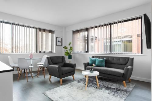 a living room with a couch and chairs and windows at Abbott House by Viridian Apartments in St. Albans