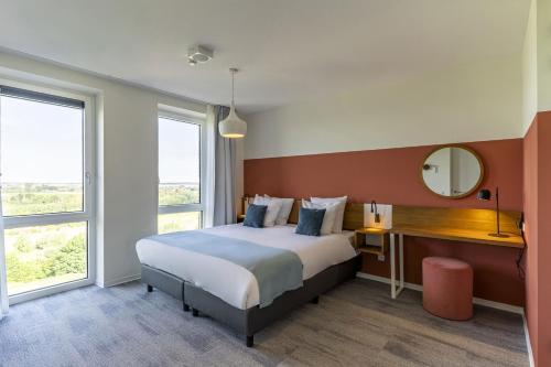a bedroom with a bed and a desk with a mirror at Dormio Hotel De Prins van Oranje in Maastricht