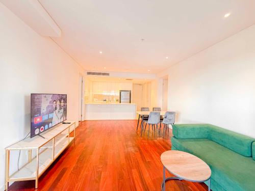 a living room with a couch and a tv at Burwood Grand Service Apartment in Sydney