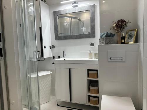 a white bathroom with a sink and a mirror at Przytulny Apartament z Balkonem Stalowa Wola in Stalowa Wola