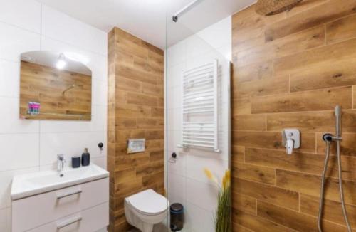 a bathroom with a toilet and a shower with wooden walls at Perła Bałtyku - kawalerka z dostępem do Resort &MediSpa in Sianozety