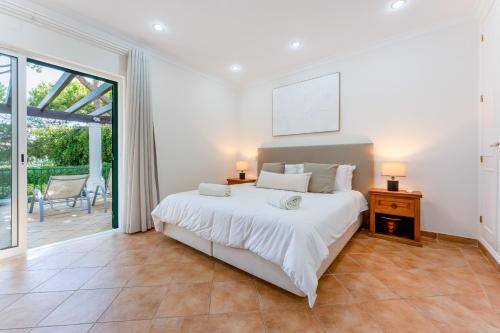 a bedroom with a large white bed and a sliding glass door at Villa Mia - Vale do Lobo in Vale do Lobo